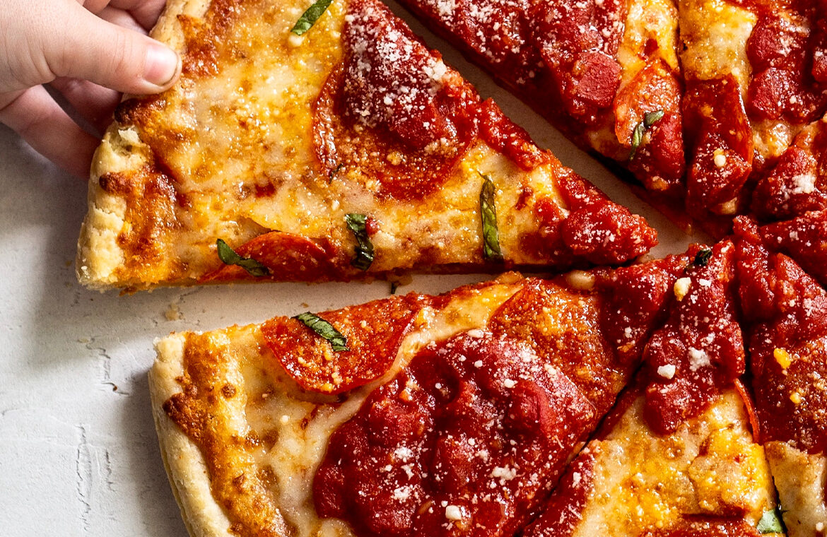 Pizza topped with pepperoni and crushed tomatoes