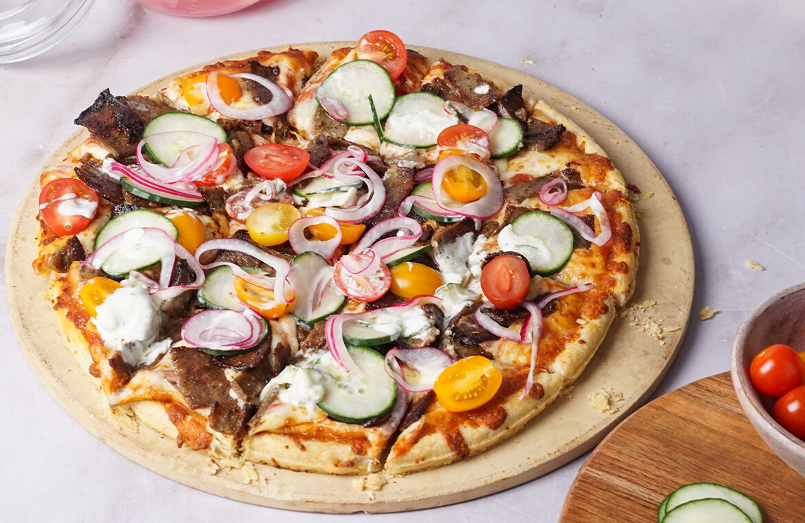 pizza topped with gyro mean, onions, cheese and greens