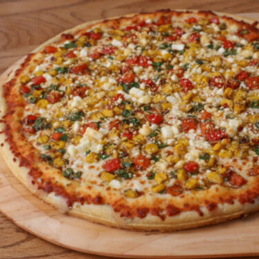 Pizza topped with corn and other fresh ingredients