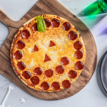 Pizza topped with pepperoni to resemble a jack-o-lantern face