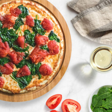 Pizza topped with plum tomato and spinach