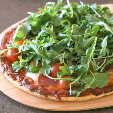 Pizza topped with cherry tomatoes and arugula