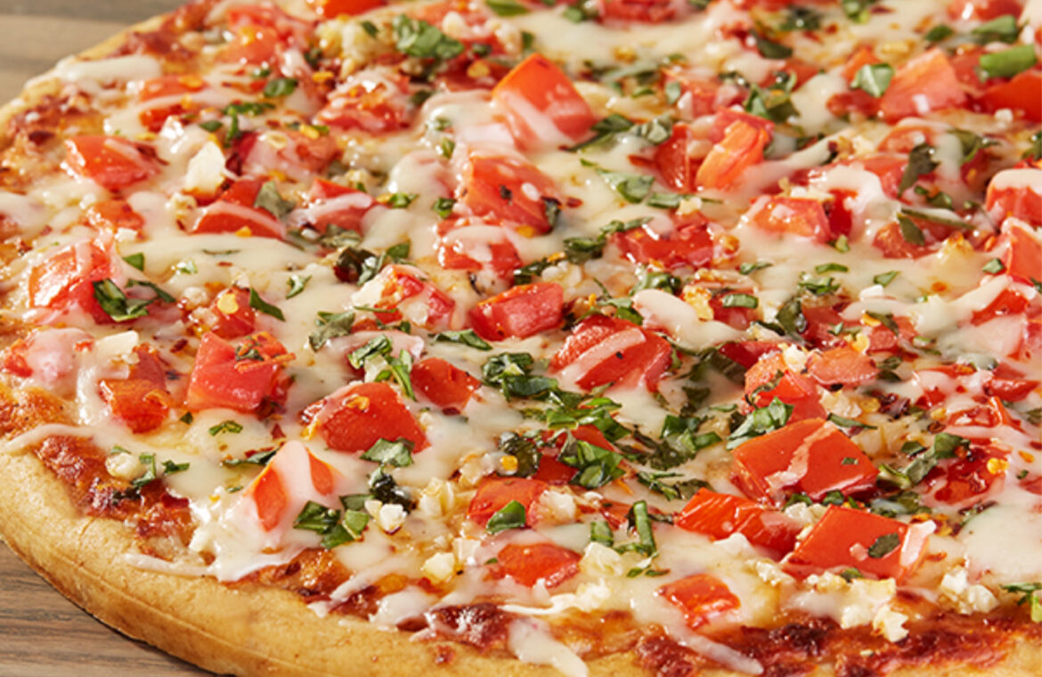 Pizza topped with diced tomatoes chili pepper flakes and fresh basil