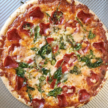 Turkey pepperoni pizza with spinach and arugula