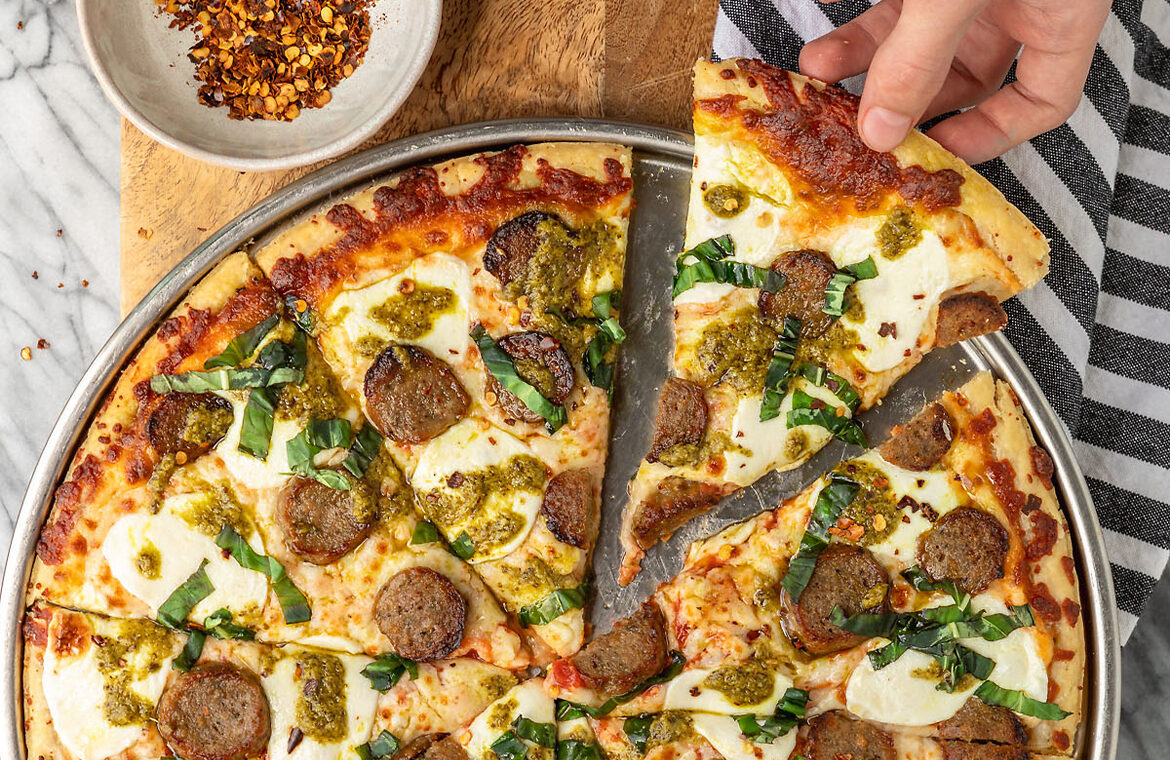 Pizza topped with meatballs and pesto