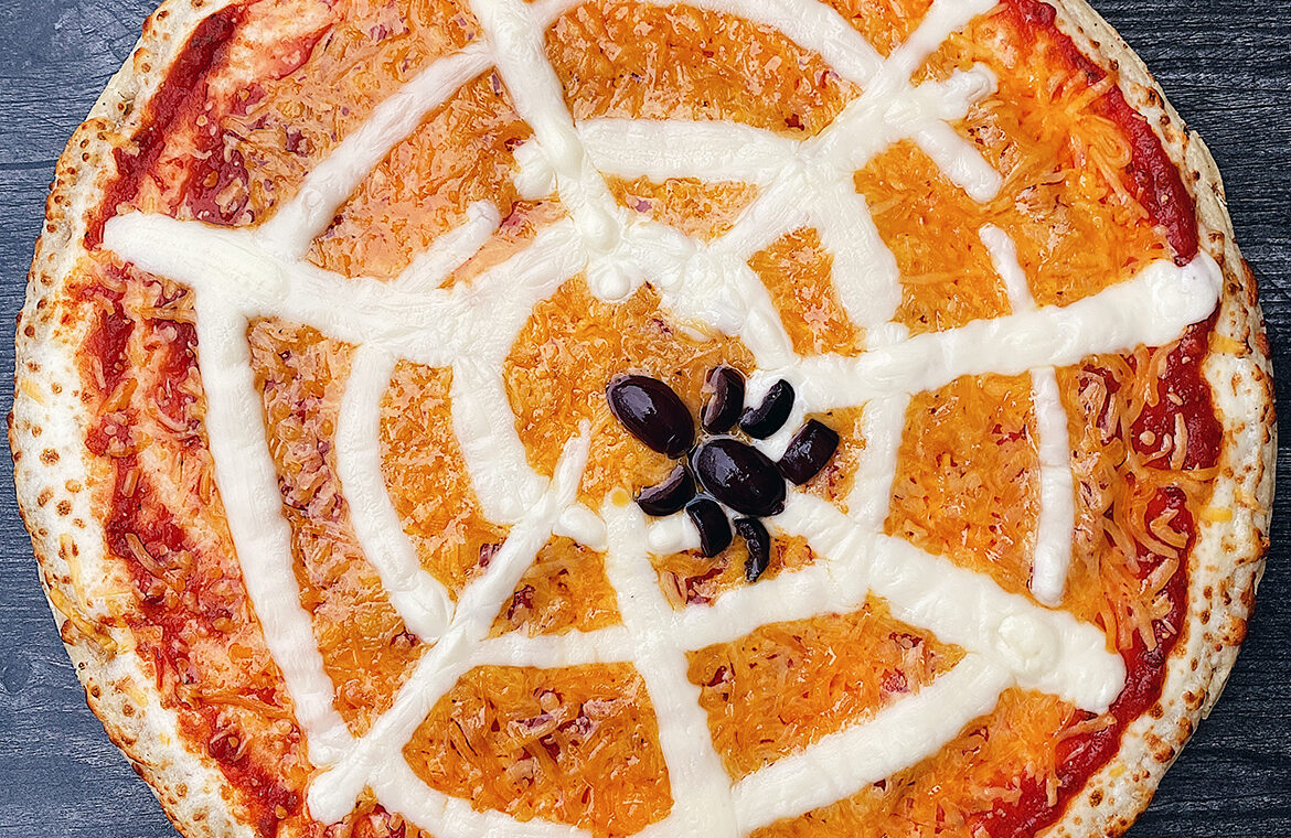 Pizza with toppings in the shape of a spider web with a spider