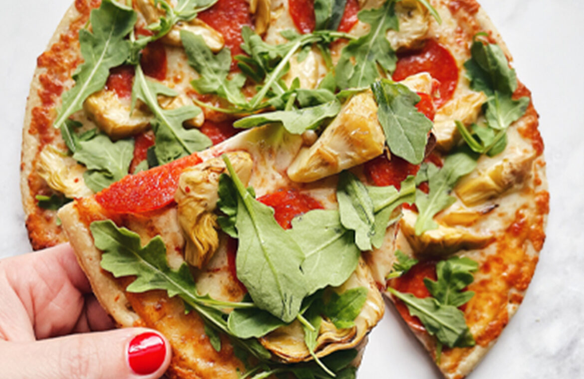 Pizza topped with artichoke, greens, and pepperoni