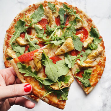 Pizza topped with artichoke, greens, and pepperoni