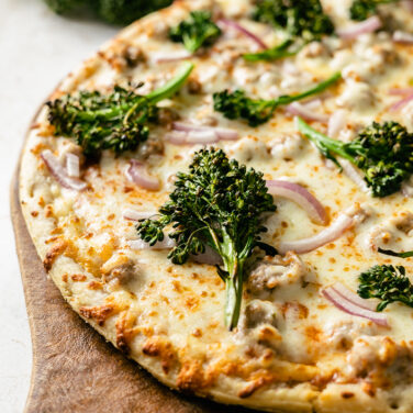 Sausage pizza topped with broccoli and red onion
