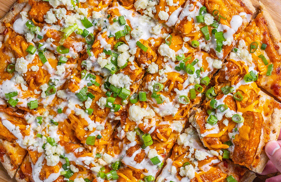 Pizza topped with chicken, green onions, buffalo sauce, and more