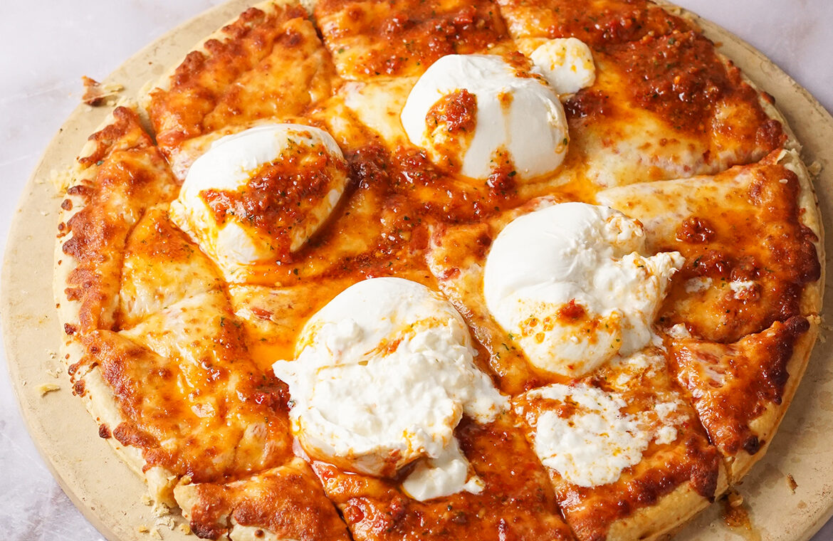 Pizza topped with burrata cheese and sun dried tomato
