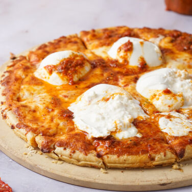 Pizza topped with burrata cheese and sun dried tomato
