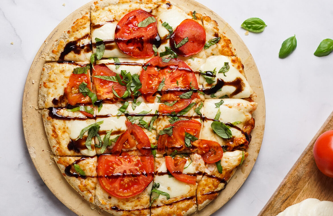 Pizza topped with fresh mozzarella, tomatoes, basil, and balsamic