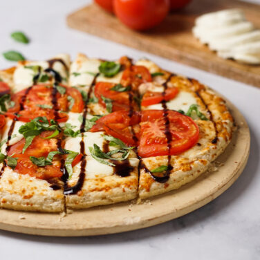 Pizza topped with fresh mozzarella, tomatoes, basil, and balsamic