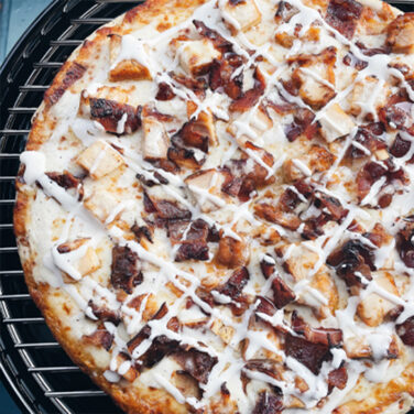 Pizza topped with chicken, bacon, and ranch
