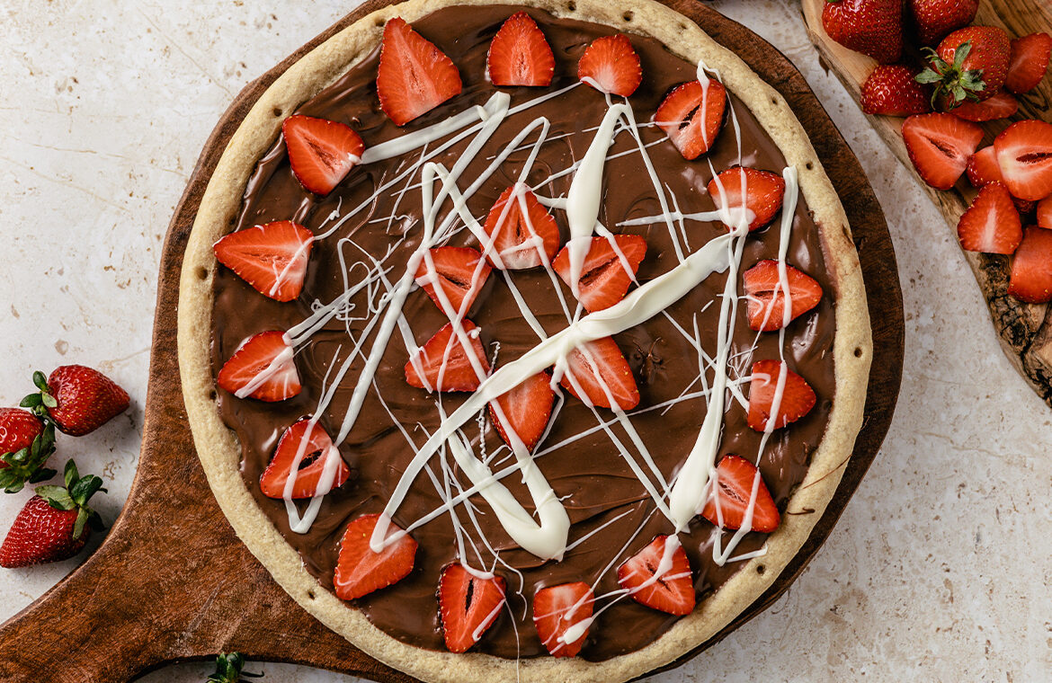 Pizza crust topped with chocolate spread and strawberries