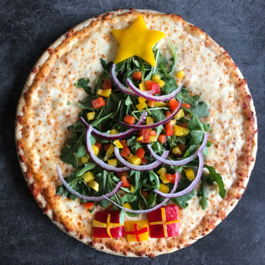 Pizza decorating with topping in the shape of a large Christmas tree