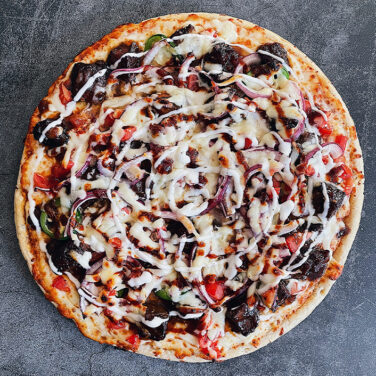 Grilled pizza topped with brisket and other toppings
