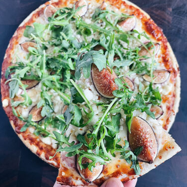 Pizza topped with fig and arugula