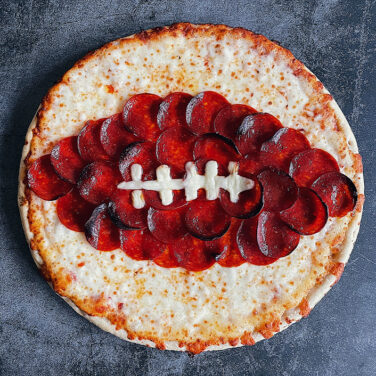 Pizza topped with pepperoni in the shape of a football