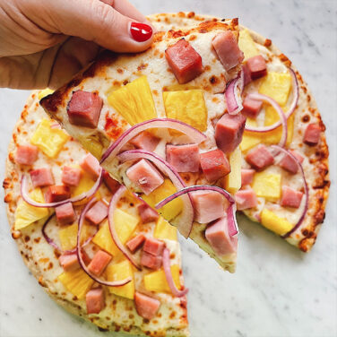 pizza topped with pineapple, ham and red onion