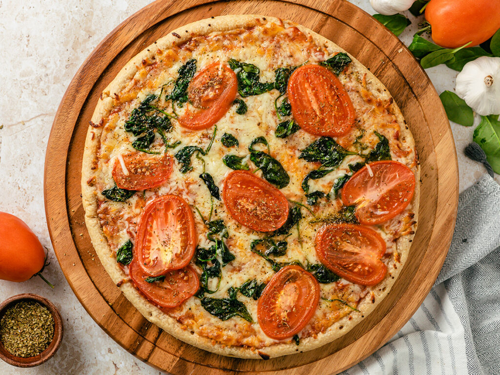 Pizza topped with tomatoes and spinach