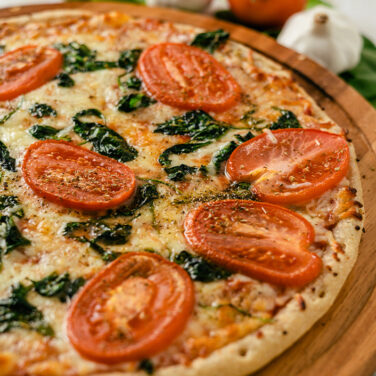 Pizza topped with tomatoes and spinach