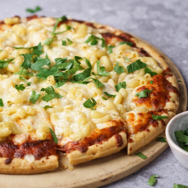 Pizza topped with macaroni and cilantro