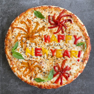 Pizza with toppings spelling out "Happy New Year"