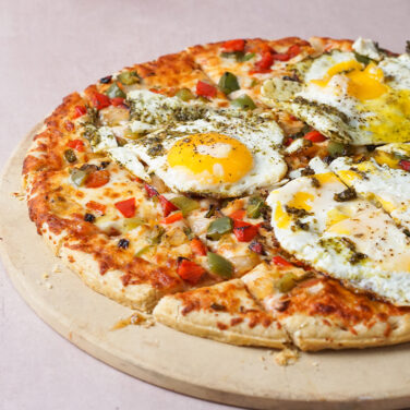 Veggie pizza topped with egg and pesto