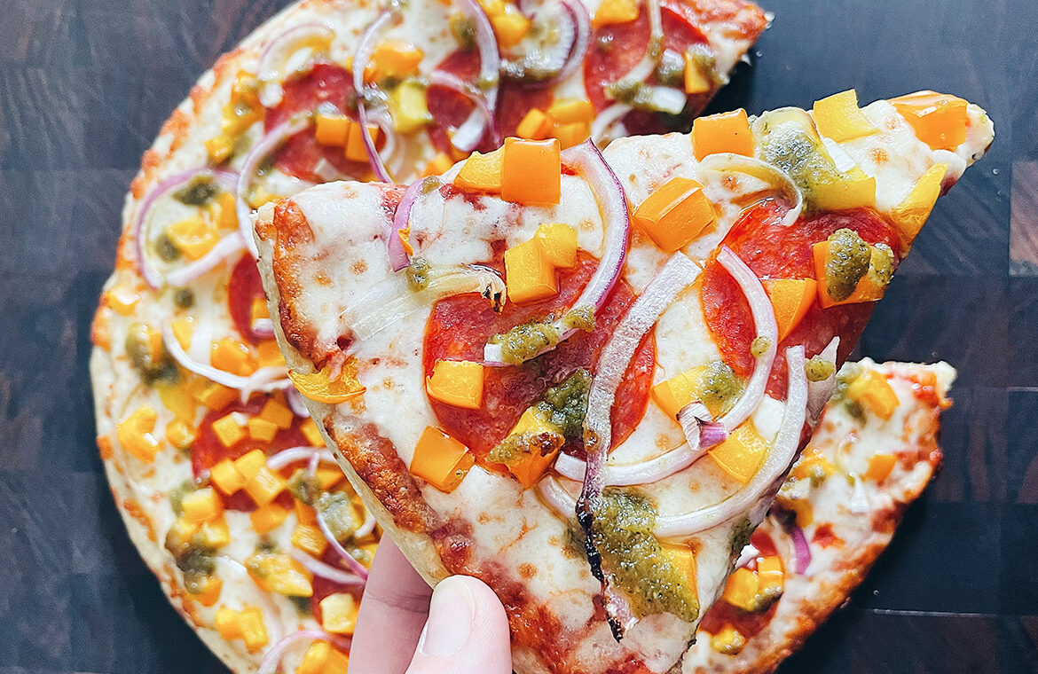 Pizza topped with pesto drizzle and other ingredients