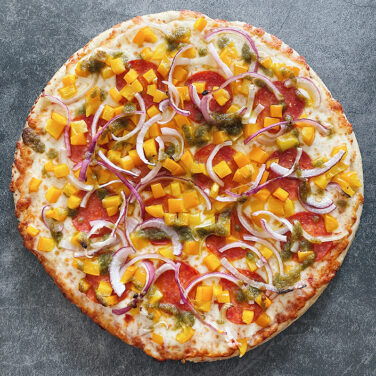 Pizza topped with pesto drizzle and other ingredients