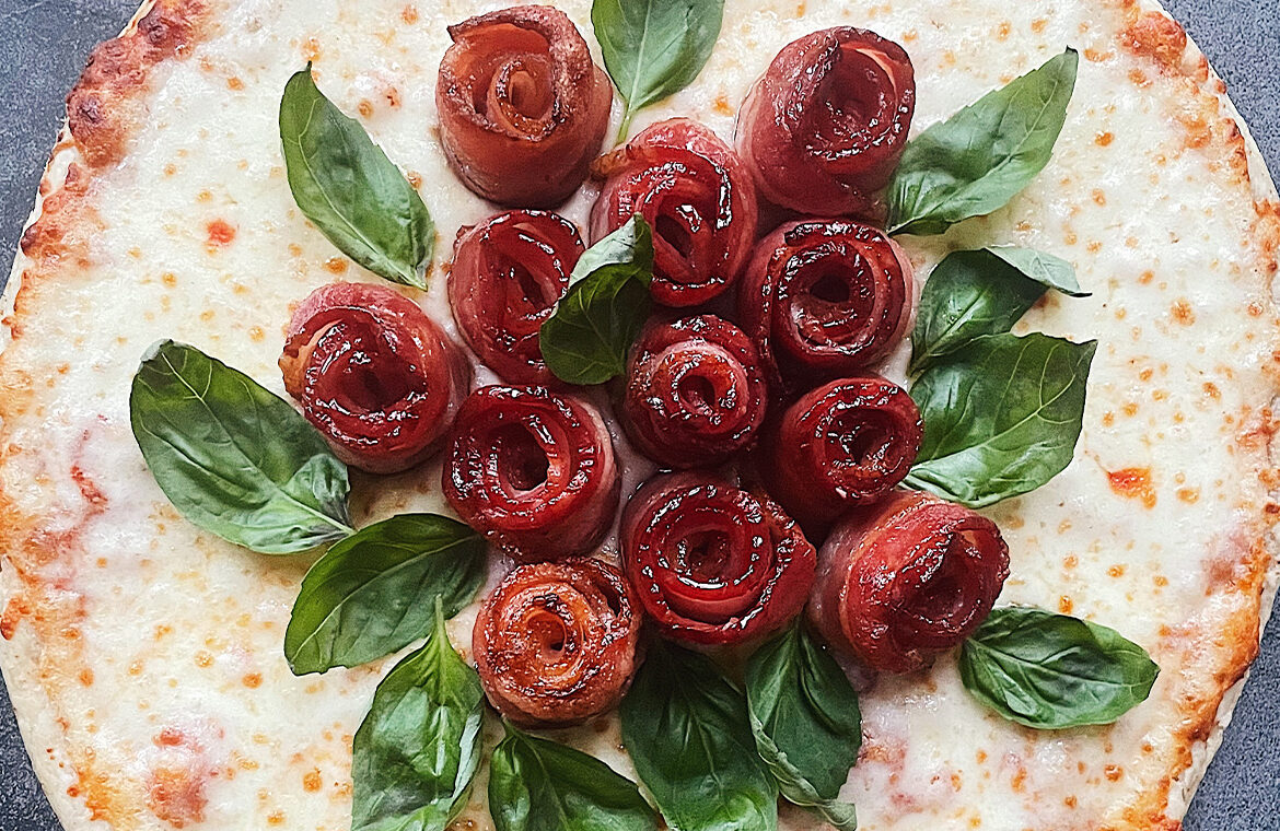 Pizza topped with bacon rolled up to look like roses