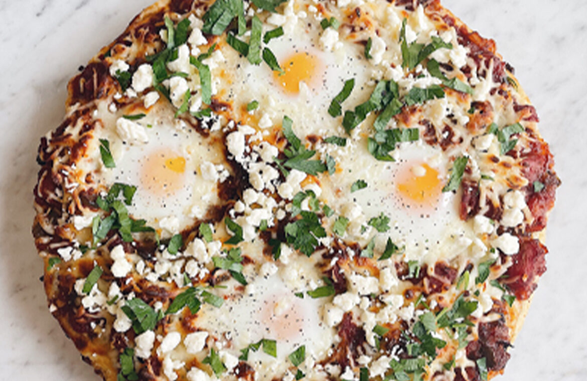 Pizza topped with eggs cheese and spiced tomato pepper sauce