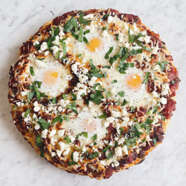 Pizza topped with eggs cheese and spiced tomato pepper sauce