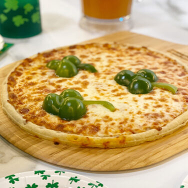 Pizza topped with peppers in the shape of a clover