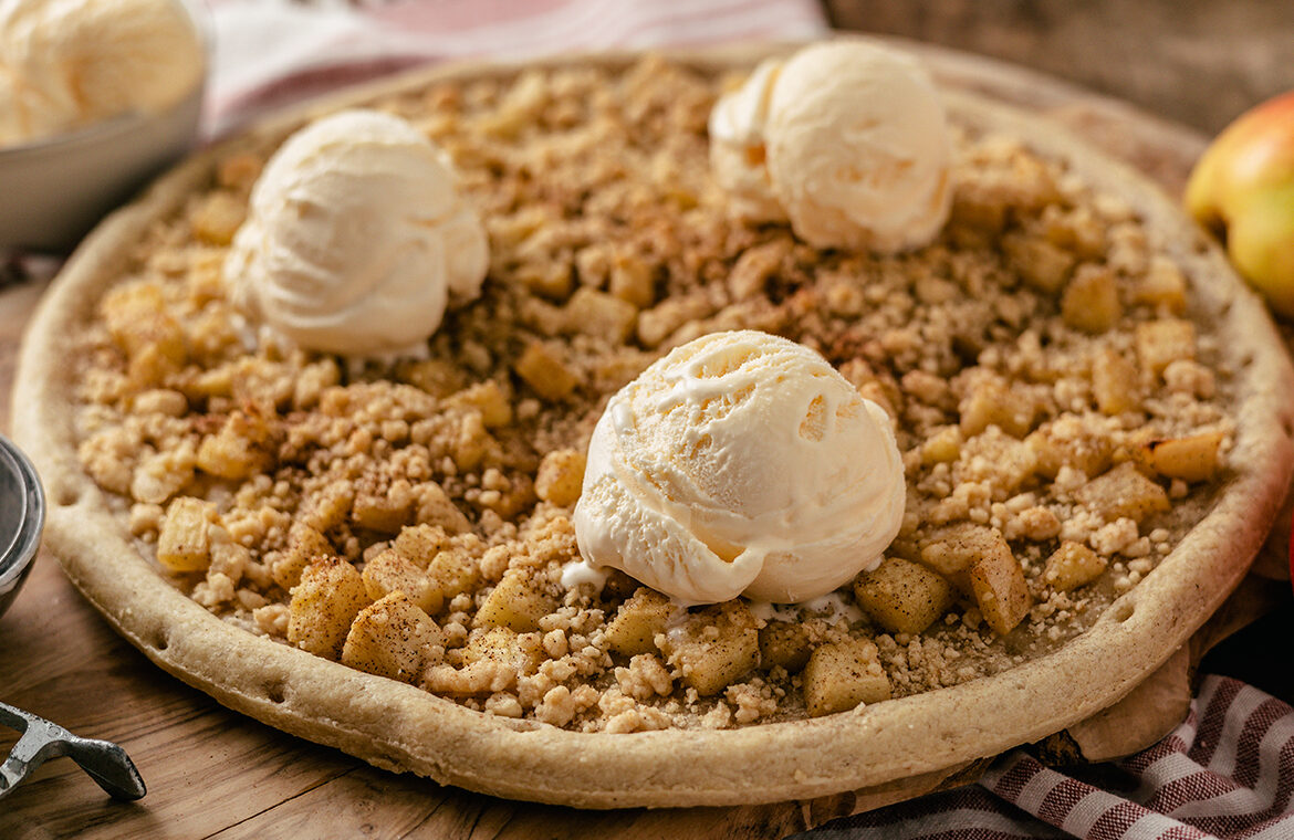 Pizza crust topped with apples, crumble, and ice cream