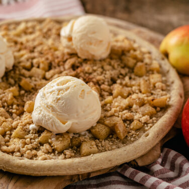 Pizza crust topped with apples, crumble, and ice cream