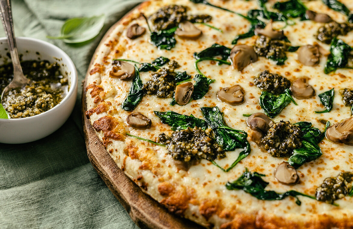 Pizza topped with pesto and spinach