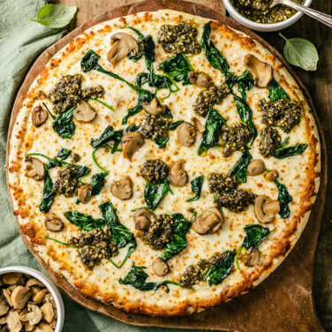 Pizza topped with pesto and spinach