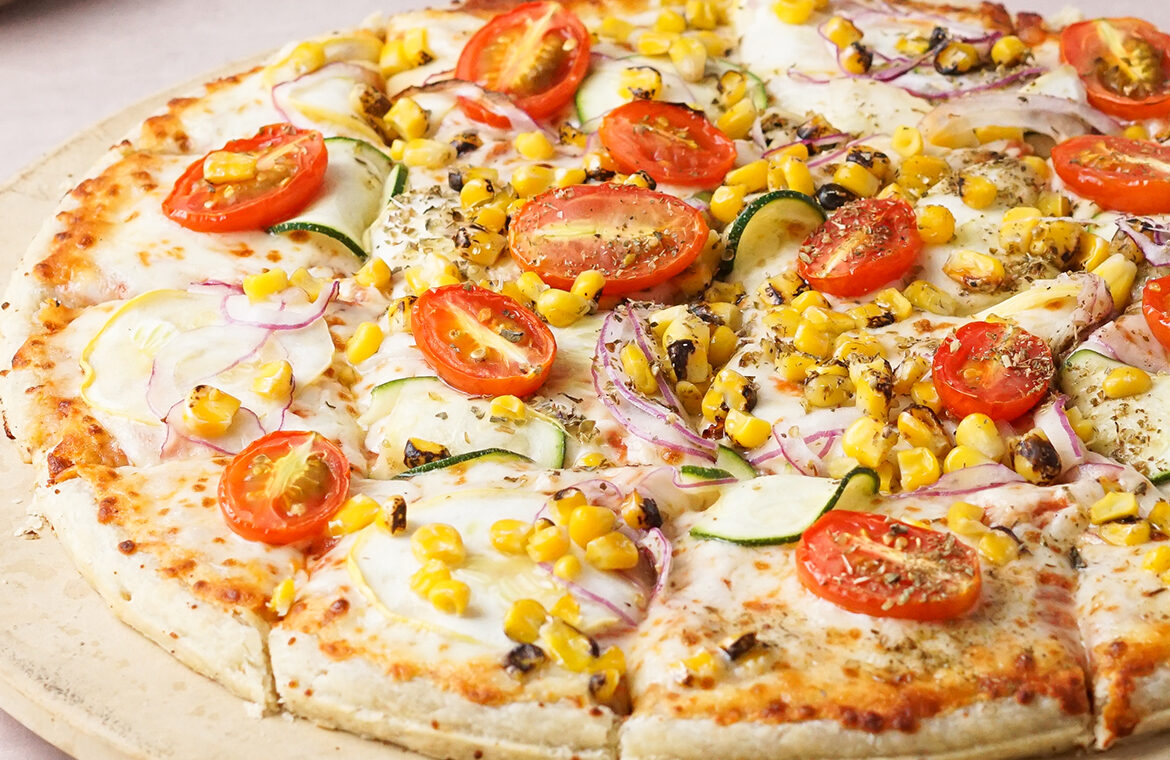 Pizza topped with corn, tomatoes, onion, and more