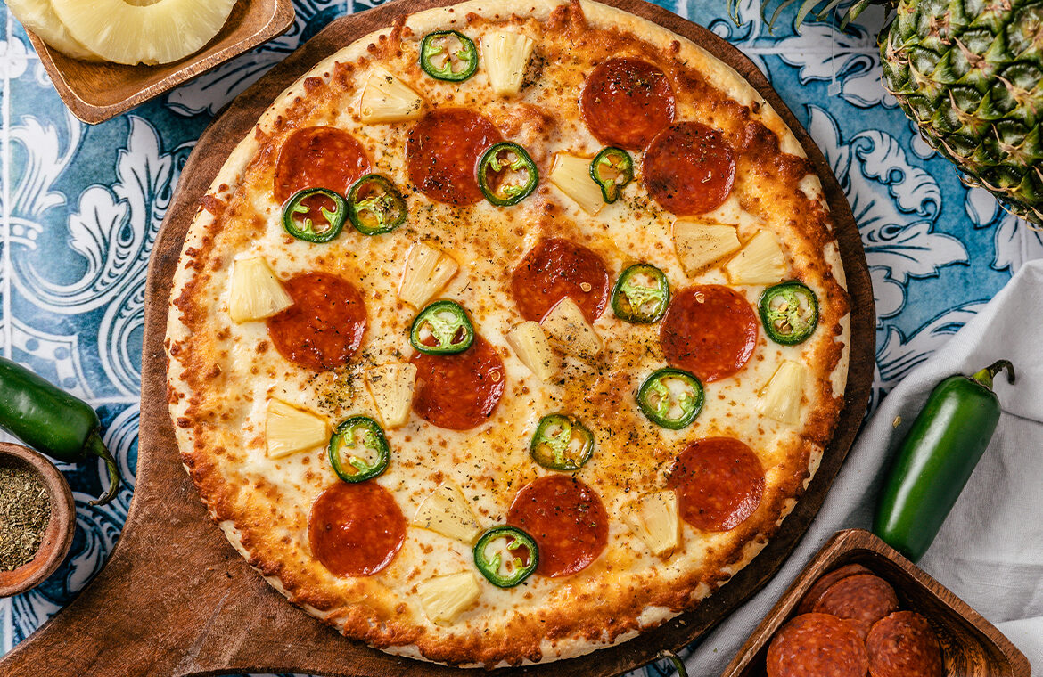 Pizza topped with jalapeno, pepperoni, and pineapple