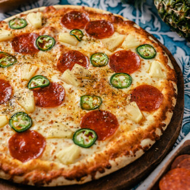 Pizza topped with jalapeno, pepperoni, and pineapple