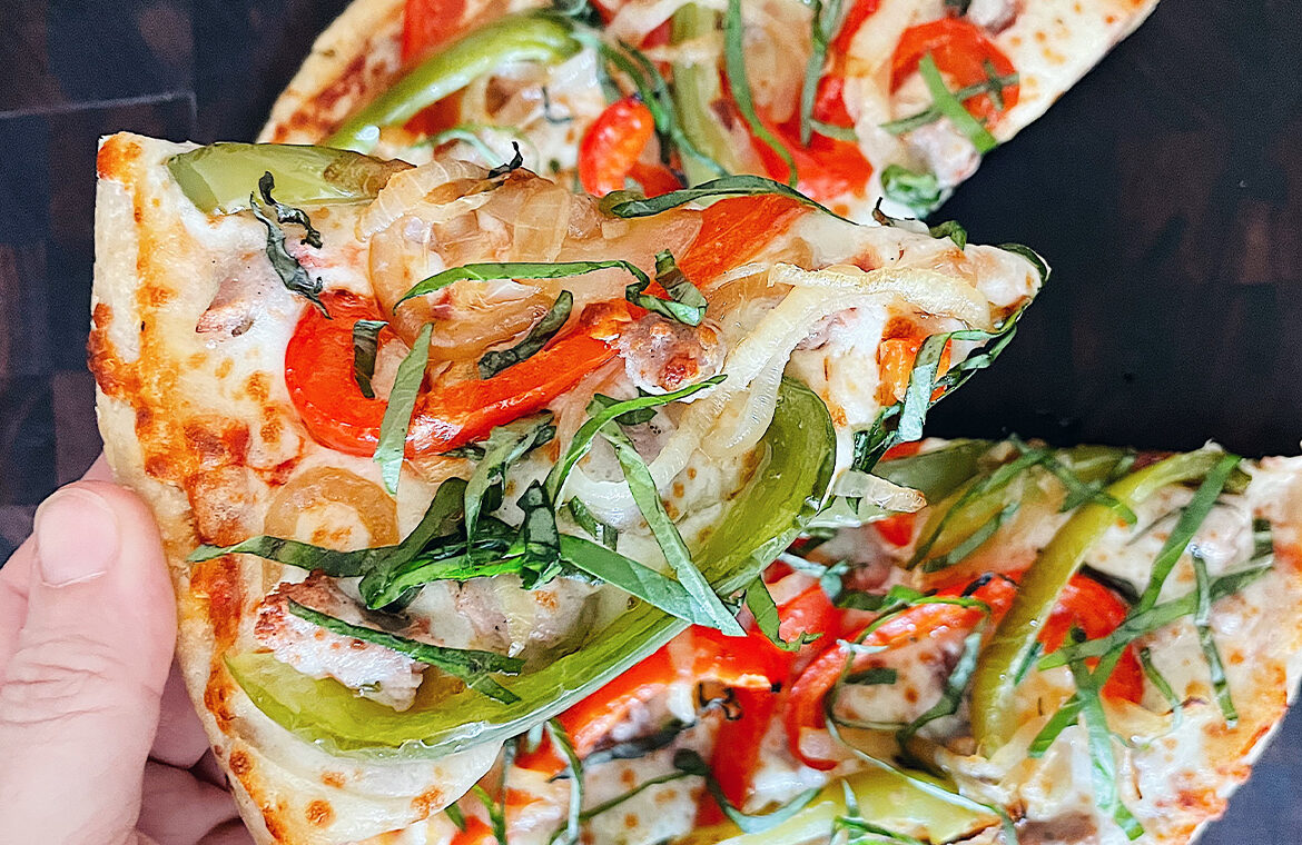 Pizza topped with peppers, onion, and basil