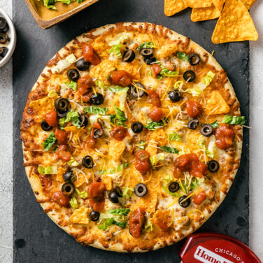 Pizza topped with taco ingredients and doritos