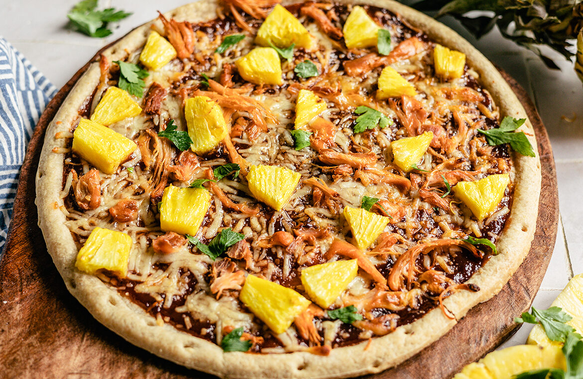 pizza topped with bbq sauce, pineapple, cheese and more