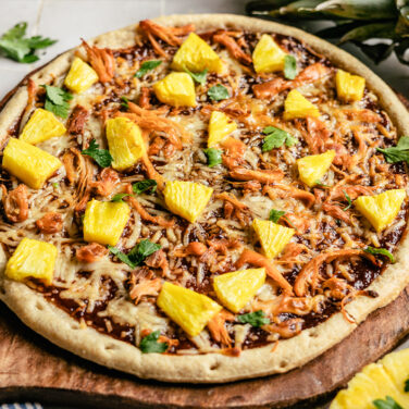 pizza topped with bbq sauce, pineapple, cheese and more