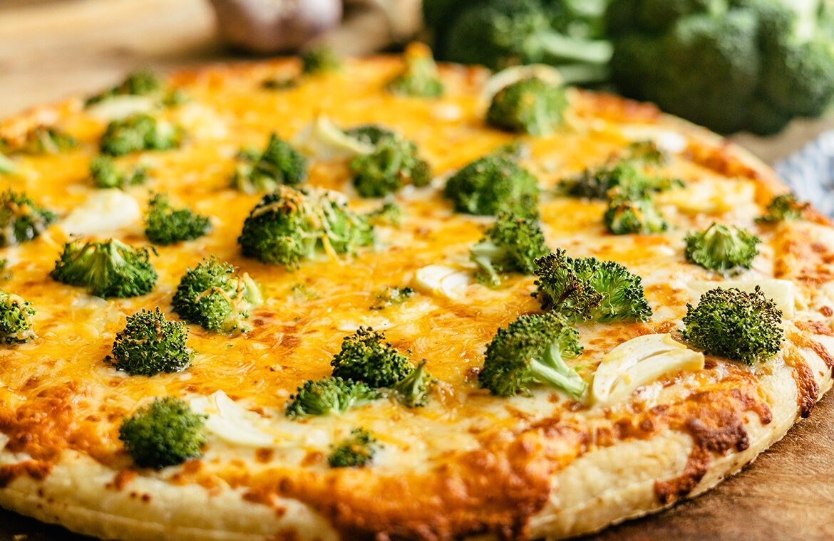 Pizza topped with cheddar cheese, broccoli, and more