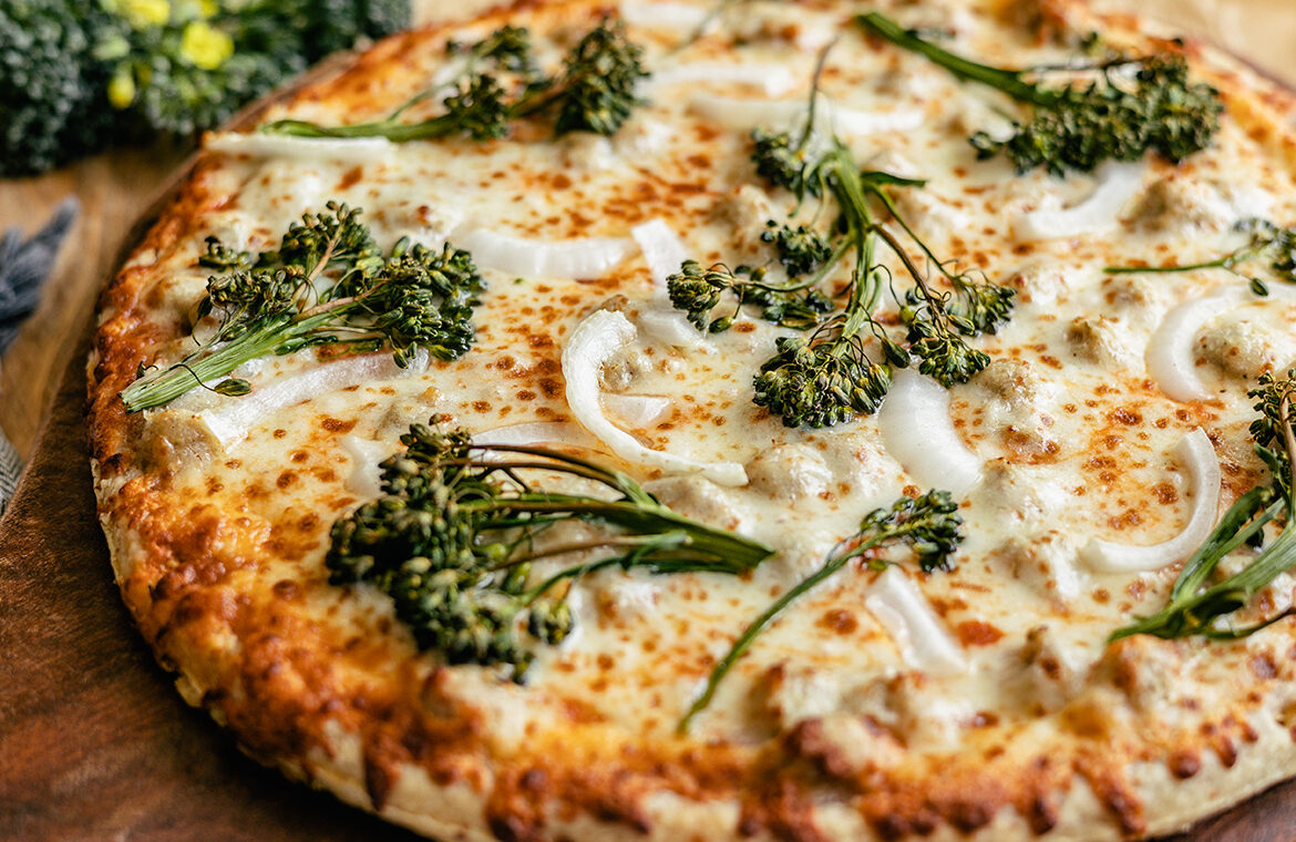 pizza topped with broccoli, onion, and more