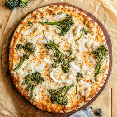 pizza topped with broccoli, onion, and more